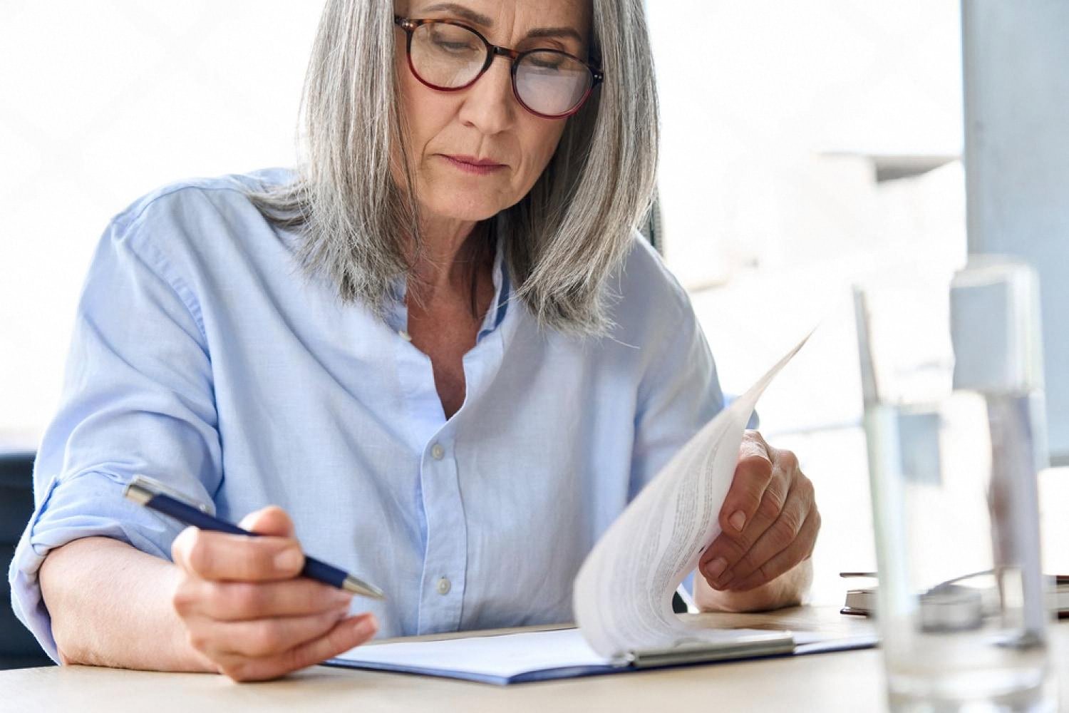 Analyst in glasses carefully reading a printed document during a company background check